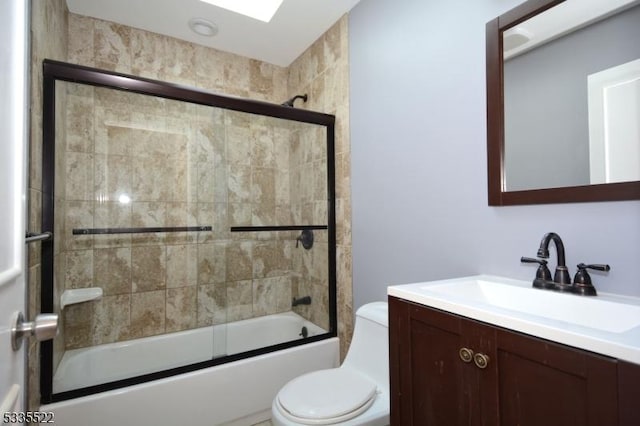 full bathroom with bath / shower combo with glass door, vanity, and toilet