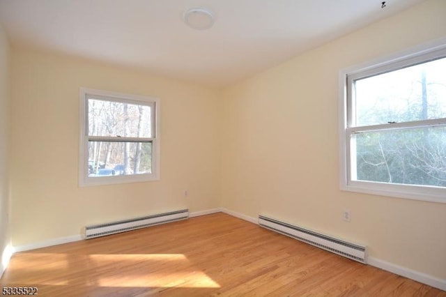 unfurnished room featuring a baseboard radiator and light hardwood / wood-style flooring