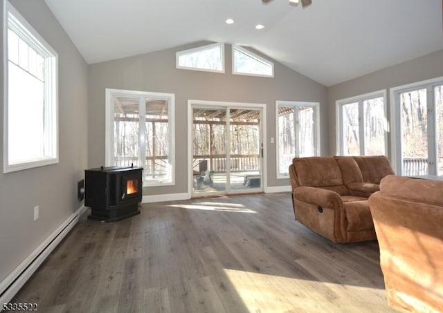 living room featuring hardwood / wood-style flooring, vaulted ceiling, a wood stove, and baseboard heating