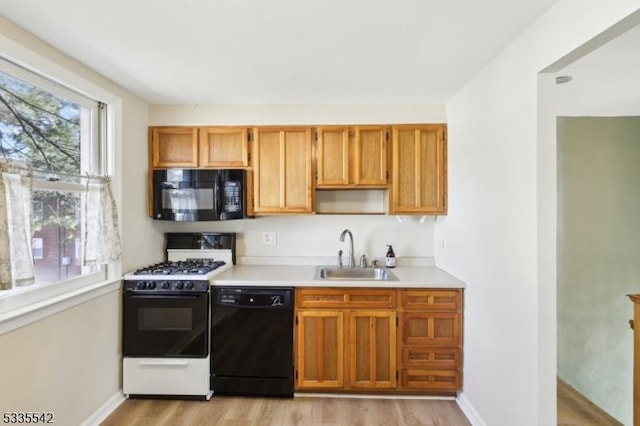 kitchen featuring light wood-type flooring, sink, and black appliances