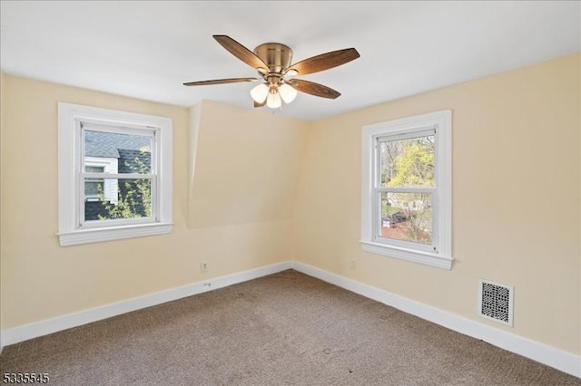 empty room with baseboards, a ceiling fan, visible vents, and carpet flooring