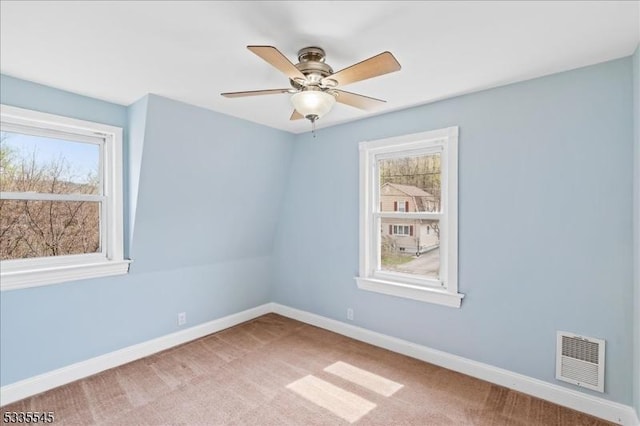 empty room featuring baseboards, visible vents, carpet, and ceiling fan