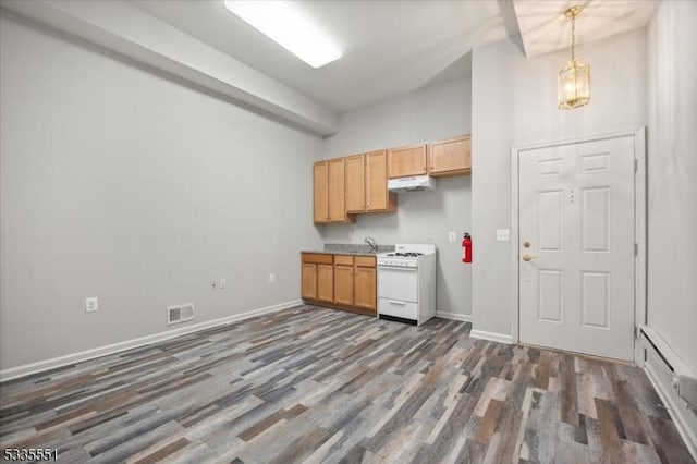 kitchen featuring dark hardwood / wood-style floors, white gas range, light brown cabinetry, and pendant lighting