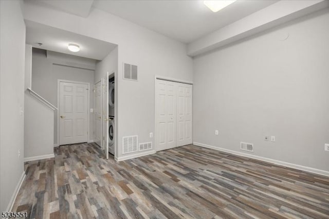 unfurnished bedroom with stacked washer / dryer and hardwood / wood-style floors