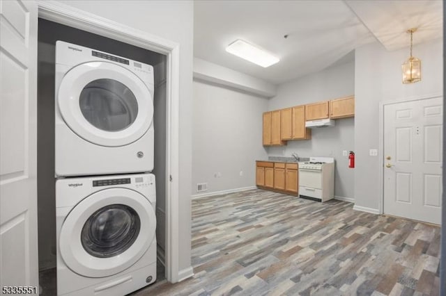 washroom with stacked washing maching and dryer and hardwood / wood-style floors