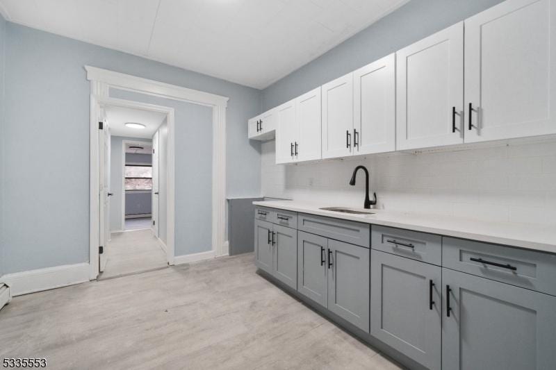 kitchen featuring white cabinetry, sink, and gray cabinetry