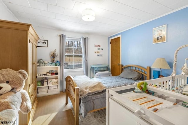 bedroom with crown molding and light hardwood / wood-style flooring