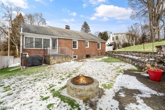 snow covered property with a sunroom and a fire pit