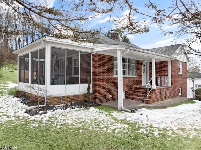 view of snowy exterior with a yard and a sunroom