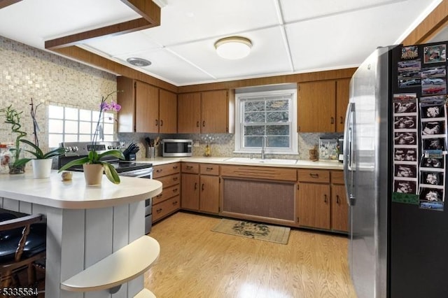 kitchen with appliances with stainless steel finishes, sink, a wealth of natural light, and light hardwood / wood-style floors