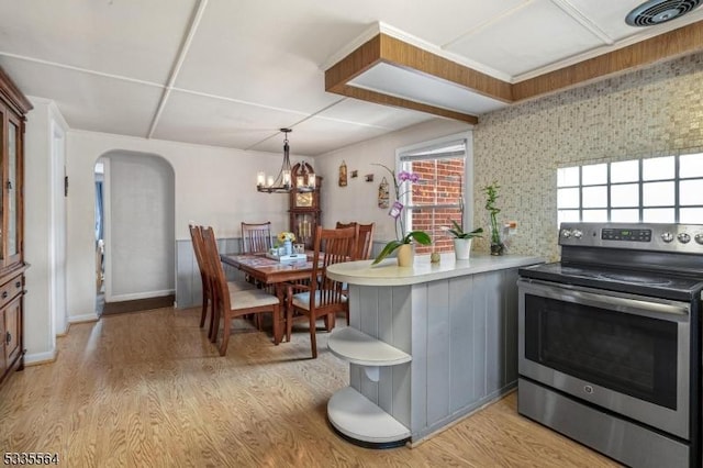 kitchen with electric stove, a chandelier, kitchen peninsula, and light hardwood / wood-style floors