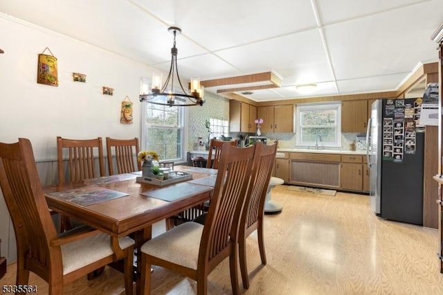 dining space featuring an inviting chandelier, sink, light hardwood / wood-style flooring, and a wealth of natural light