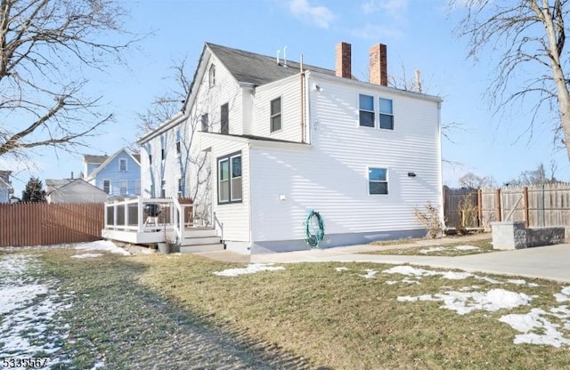 back of house with a wooden deck and a lawn