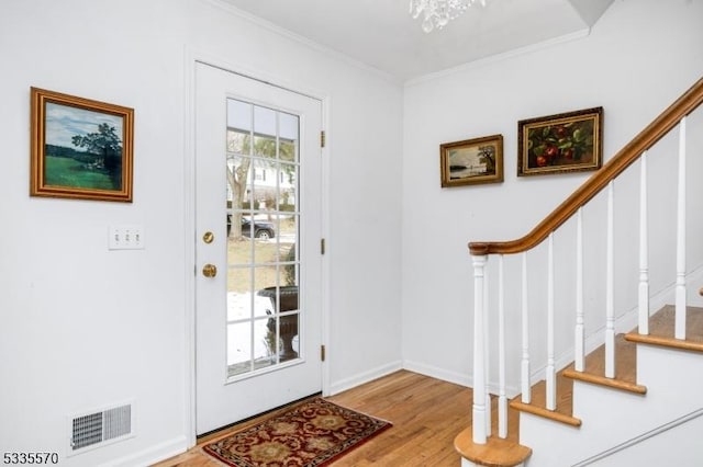 foyer entrance with crown molding and light hardwood / wood-style floors