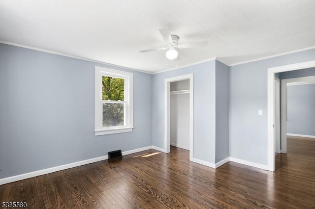 unfurnished bedroom featuring dark wood-type flooring, ceiling fan, ornamental molding, and a closet