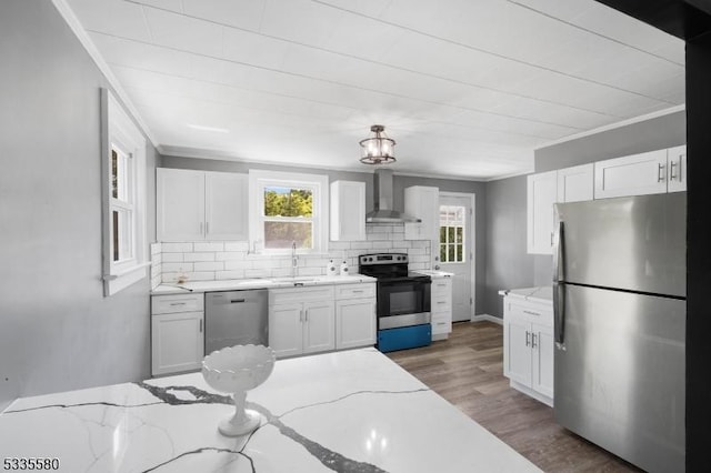 kitchen with stainless steel appliances, white cabinetry, light stone counters, and wall chimney exhaust hood