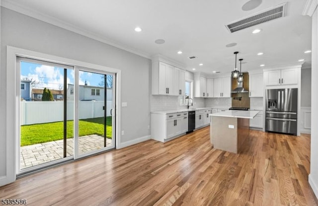 kitchen featuring a kitchen island, decorative light fixtures, white cabinets, stainless steel fridge with ice dispenser, and wall chimney exhaust hood