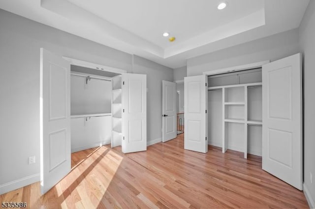 unfurnished bedroom featuring a tray ceiling and light hardwood / wood-style flooring