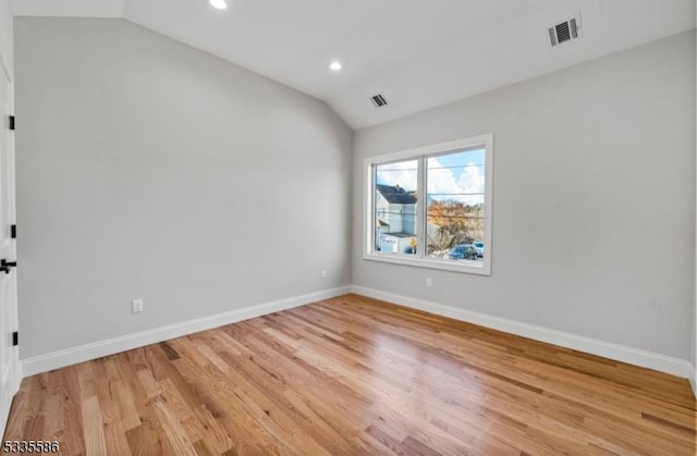 unfurnished room with lofted ceiling and light wood-type flooring