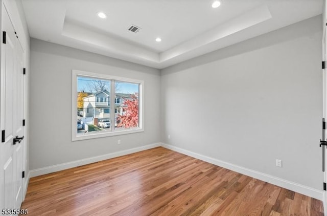 empty room featuring a raised ceiling and light wood-type flooring