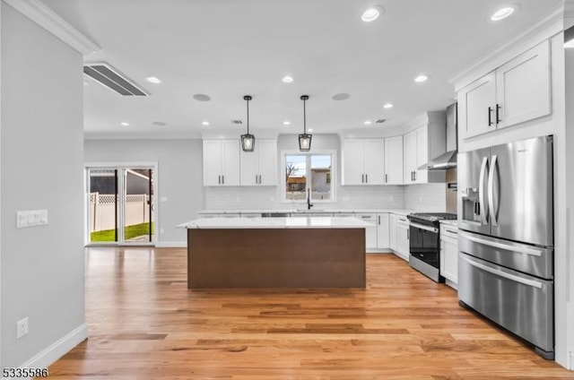 kitchen with white cabinetry, stainless steel appliances, a center island, and wall chimney range hood