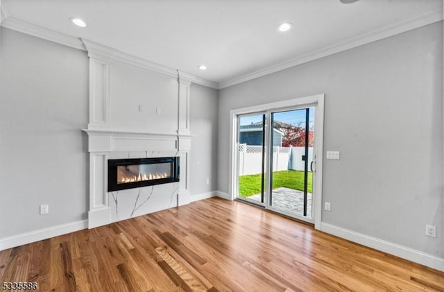 unfurnished living room featuring ornamental molding, a large fireplace, and light hardwood / wood-style floors