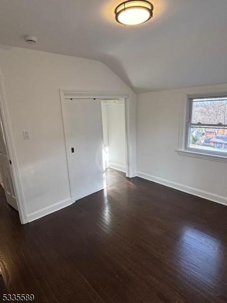 interior space with dark wood-type flooring and vaulted ceiling