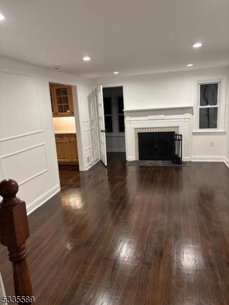 unfurnished living room with dark wood-type flooring and a tiled fireplace