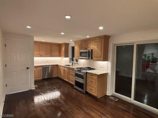 kitchen with dark hardwood / wood-style floors, sink, decorative backsplash, stainless steel appliances, and light stone countertops