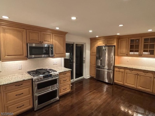 kitchen featuring dark hardwood / wood-style flooring, light stone countertops, decorative backsplash, and stainless steel appliances