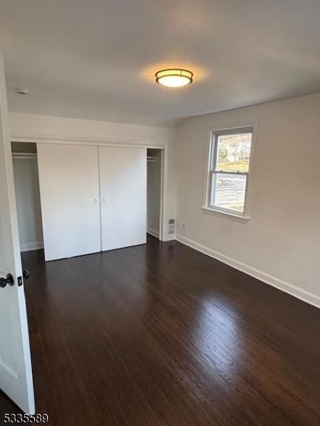 unfurnished bedroom with a closet and dark hardwood / wood-style floors