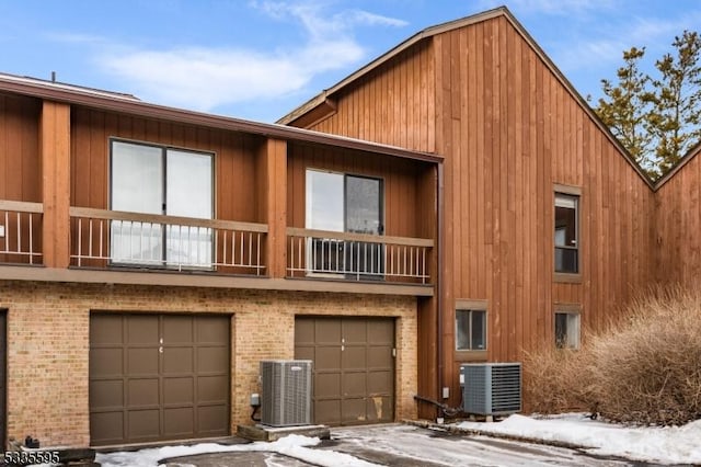 view of front of home featuring a balcony, a garage, and central air condition unit