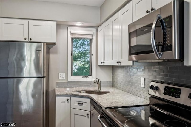 kitchen with light stone counters, sink, stainless steel appliances, and white cabinets