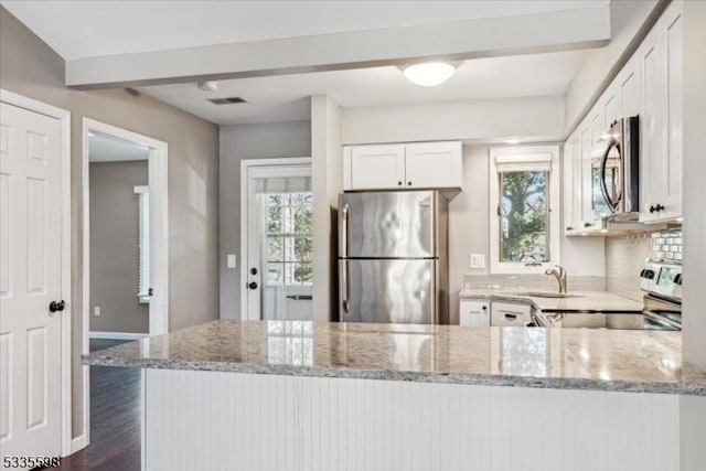 kitchen featuring stainless steel appliances, light stone countertops, and white cabinets