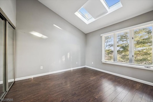 empty room with dark hardwood / wood-style flooring and vaulted ceiling with skylight