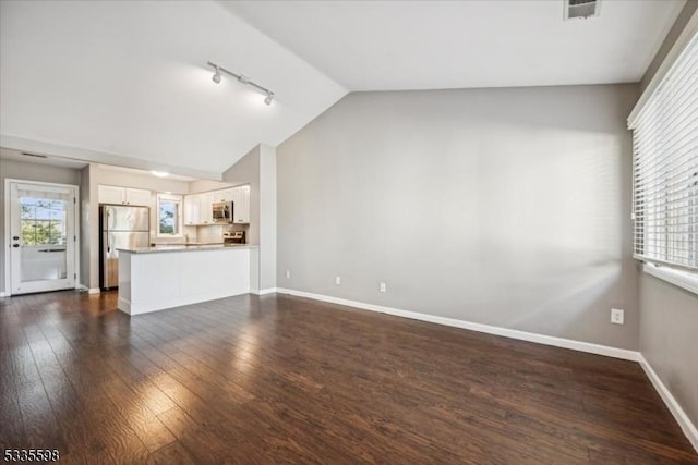 unfurnished living room featuring vaulted ceiling, rail lighting, and dark hardwood / wood-style flooring