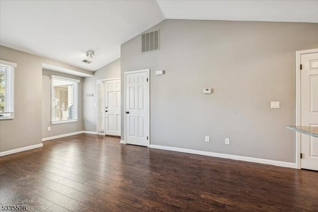 spare room featuring dark wood-type flooring and lofted ceiling