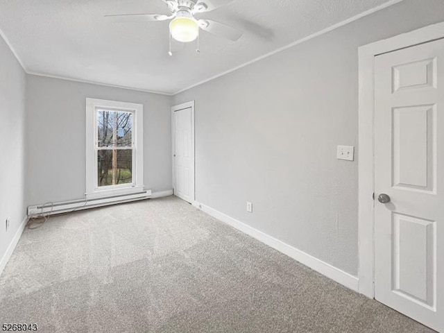 carpeted spare room featuring ornamental molding, ceiling fan, and baseboard heating