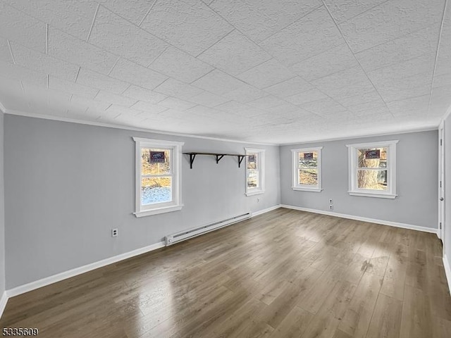 unfurnished room featuring a baseboard heating unit, ornamental molding, and hardwood / wood-style floors