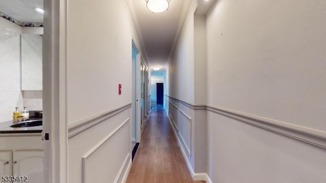 corridor with hardwood / wood-style flooring, ornamental molding, and sink