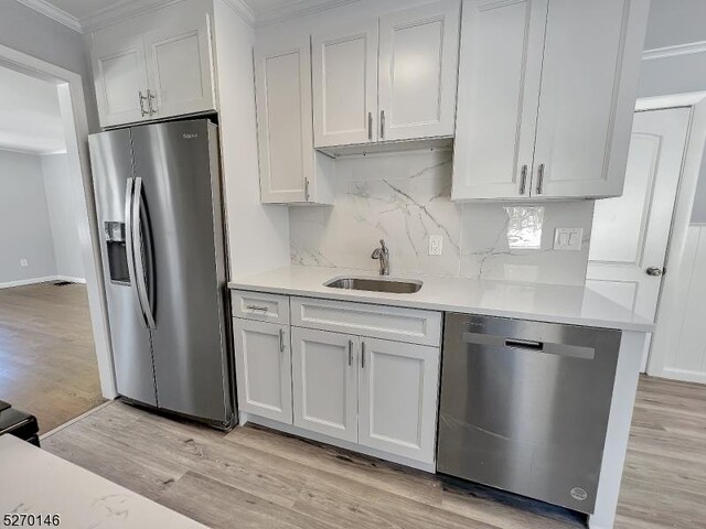 kitchen with sink, crown molding, white cabinets, and appliances with stainless steel finishes