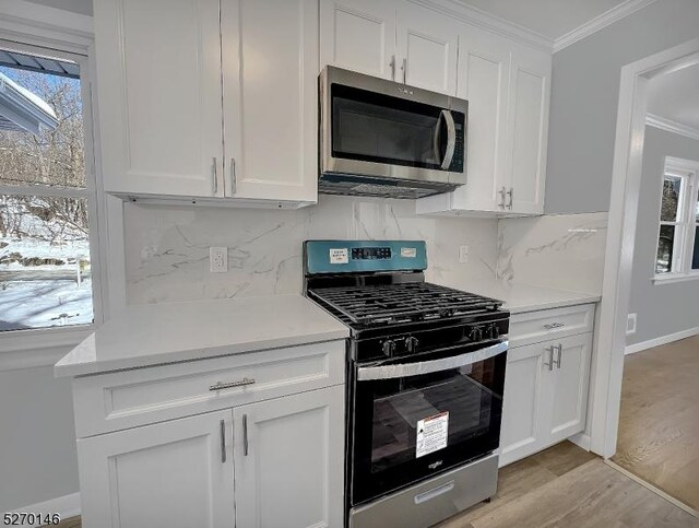 kitchen with white cabinetry, appliances with stainless steel finishes, and crown molding