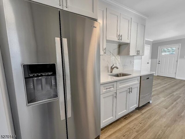 kitchen featuring sink, crown molding, light hardwood / wood-style flooring, appliances with stainless steel finishes, and white cabinets