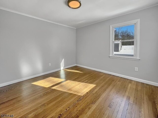 empty room with crown molding and hardwood / wood-style floors