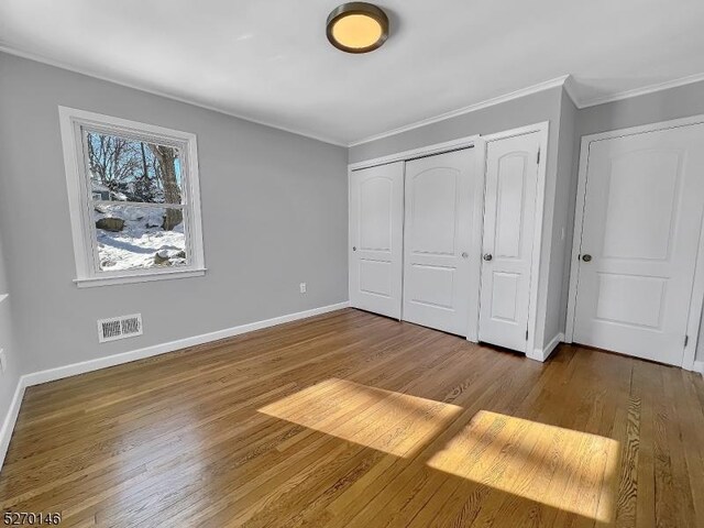 unfurnished bedroom with ornamental molding, wood-type flooring, and a closet