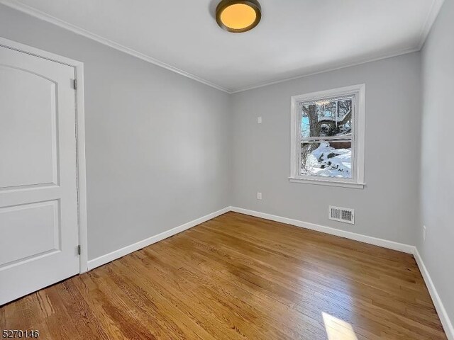 spare room with ornamental molding and light wood-type flooring