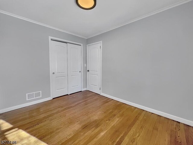 unfurnished bedroom featuring ornamental molding, wood-type flooring, and a closet