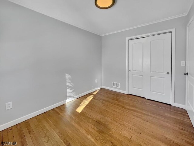 unfurnished bedroom featuring crown molding, a closet, and light hardwood / wood-style flooring