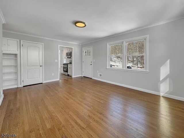 unfurnished living room featuring crown molding and hardwood / wood-style floors