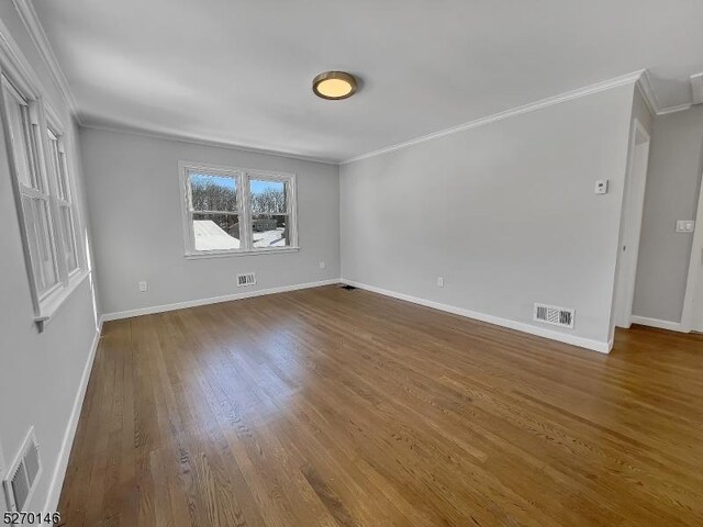 spare room featuring crown molding and hardwood / wood-style floors